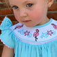 Light blue romper with flamingo embroidery and flutter sleeves on toddler.