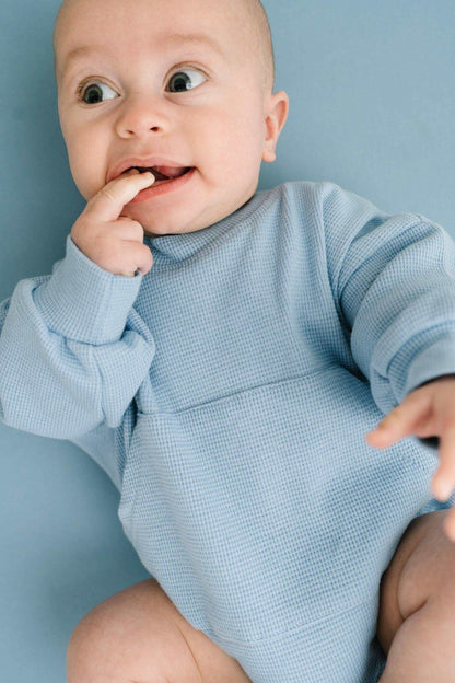 Baby wearing blue river waffle sweatshirt romper with waffle knit fabric and oversized fit
